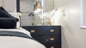 Ein modernes Schlafzimmer mit einem Bett, einer Kommode, einem Spiegel und einer Pendelleuchte.