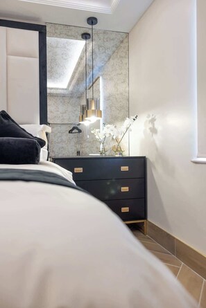 Quarto moderno com cama, penteadeira, espelho e luminária pendente.
