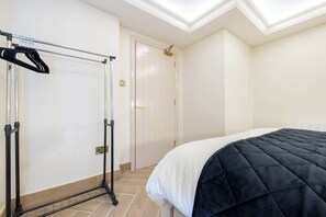 Quarto de hotel com cama, guarda-roupa, espelho e porta.