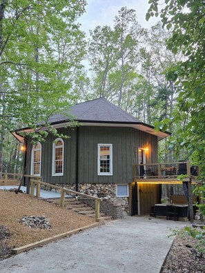 Una cabaña rústica con base de piedra, fachada de madera y un balcón con mobiliario exterior.