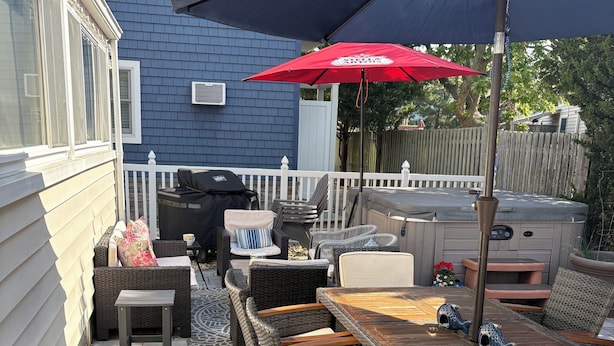 An outdoor patio with wicker furniture, a grill, and a hot tub. - Beach Block 5-Bedroom Retreat with AC in Silver Beach, Lavallette, NJ (Lavallette)