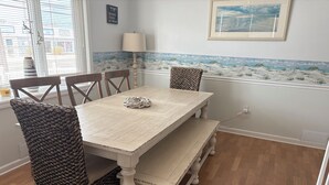 A dining area with a wooden table, four chairs, a bench, and a beach-themed wall mural. - Beach Block 5-Bedroom Retreat with AC in Silver Beach, Lavallette, NJ (Lavallette)