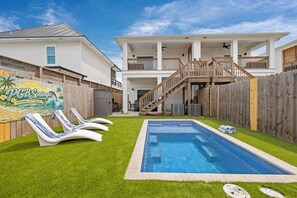 Una casa de dos pisos con piscina, una terraza de madera y un letrero que dice PCB Springs.