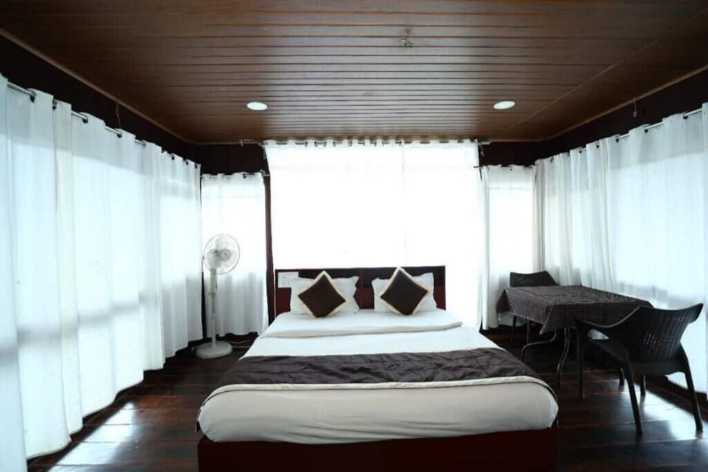 Ein Hotelzimmer mit einem großen Bett, einem Schreibtisch mit Stuhl und einem Fenster mit Vorhängen.