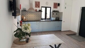 Een moderne keuken met lichtblauwe kastjes, een betegelde spatwand en een centraal eiland met een bloevas.