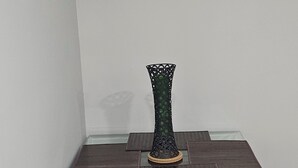 A dining table with a glass top and a decorative vase in the center.