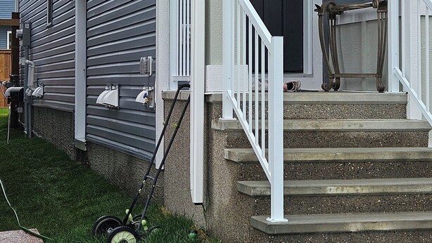 A two-story house with a front porch, a door, and a staircase leading to the entrance.