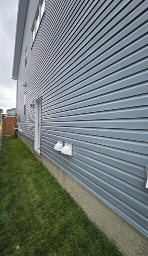 Un bâtiment moderne avec un revêtement horizontal et un petit jardin devant, avec de la pelouse.