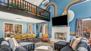 A spacious living area with a fireplace, a television, and a balcony with a railing. - WOW Pocono Private Heated Pool, Pickleball, Hottub (East Stroudsburg)