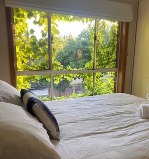 A hotel room with a large window offering a view of a garden with green foliage. - Grand Country Retreat Close to Mount Panorama and Bathurst (Robin Hill)