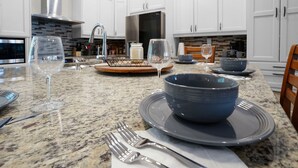 Een moderne keuken met witte kasten, granieten aanrechtbladen en roestvrijstalen apparatuur.