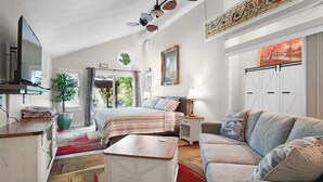 Een ruime, goed verlichte kamer met een bed, een bank, een klein tafeltje en een televisie.