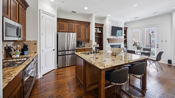 A modern kitchen with wooden cabinets, stainless steel appliances, and a marble island.