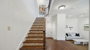 A staircase with wooden steps and a handrail, leading to a white door.