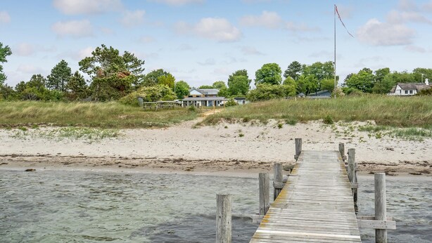 A wooden pier leading to a beach with houses in the background. - Awesome home in Sydals with WiFi (Sydals)