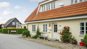 A two-story building with a red-tiled roof, a bench, and red flowers in front. - Awesome home in Sydals with WiFi (Sydals)