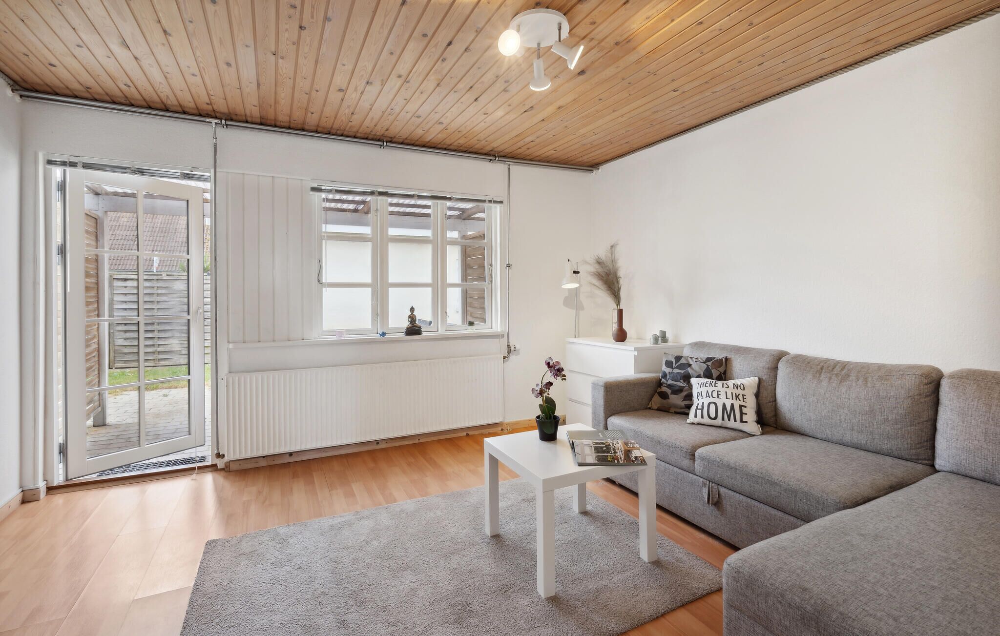 A modern living room with a grey sofa, a white coffee table, and a wooden ceiling.