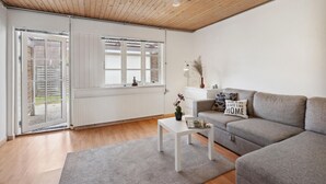 A modern living room with a grey sofa, a white coffee table, and a wooden ceiling. - Awesome home in Sydals with WiFi (Sydals)