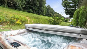 Ein Whirlpool mit Blick auf einen grünen Hügel und ein Gazebo im Hintergrund.