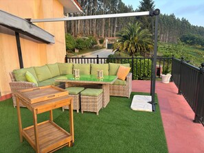 A balcony with a green artificial grass floor, wicker furniture, and a view of a forested area. - House located in the Fragas do Eume Natural Park, ideal for families. (Monfero)