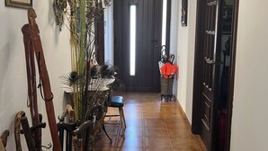 A hallway with a wooden floor, a dining table with chairs, a chandelier, and a door with a window. - House located in the Fragas do Eume Natural Park, ideal for families. (Monfero)