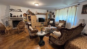 A living room with a fireplace, wooden furniture, a television, and decorative items. - House located in the Fragas do Eume Natural Park, ideal for families. (Monfero)