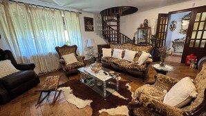 A living room with a patterned sofa, a black armchair, a glass coffee table, and a brown leather sofa. - House located in the Fragas do Eume Natural Park, ideal for families. (Monfero)