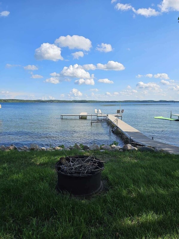 Une jetée au bord du lac, avec des chaises et un barbecue.