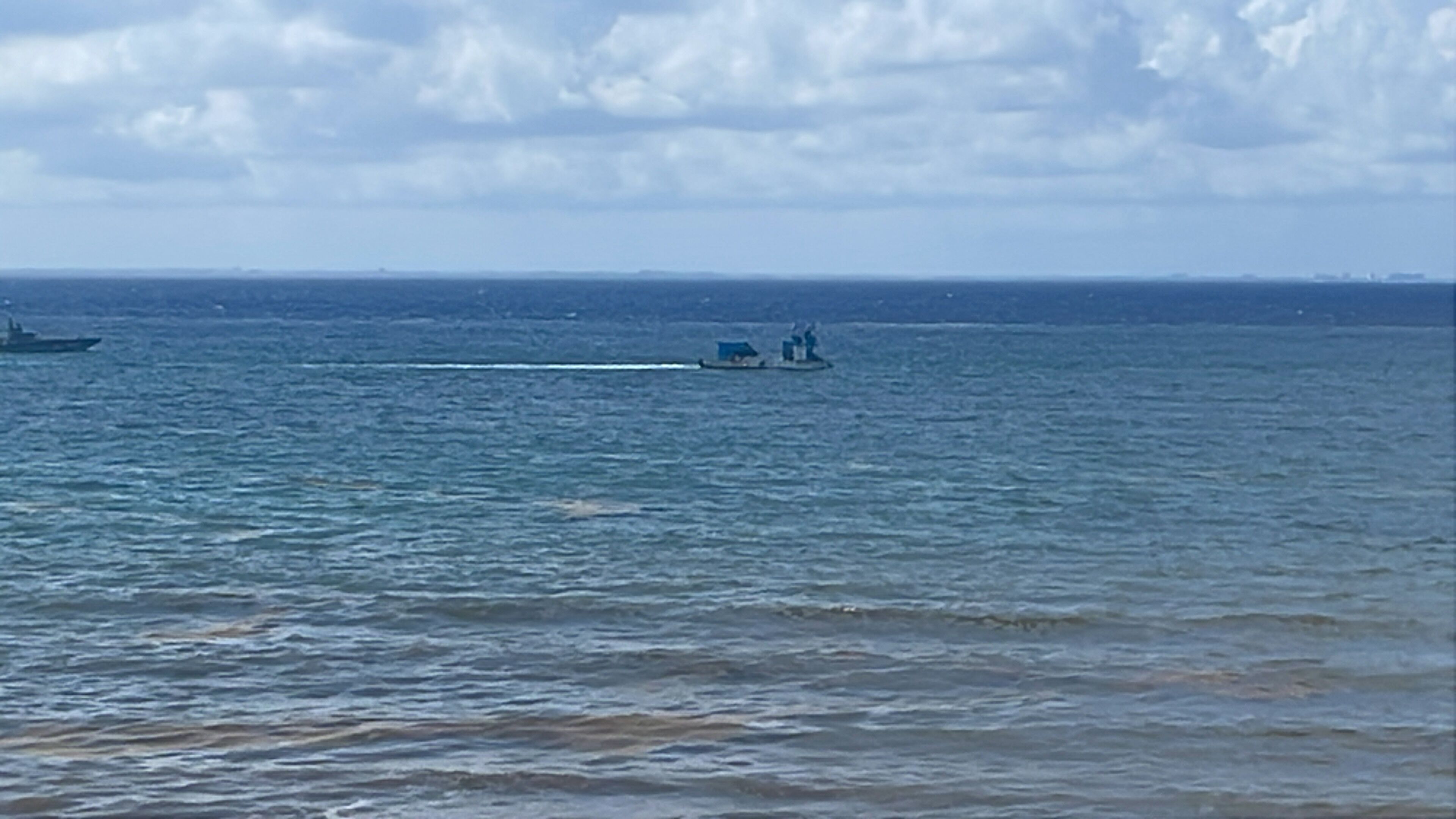 Une étendue d’eau sur laquelle on aperçoit un petit bateau et, au loin, un plus grand navire.