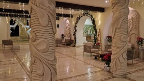 Un vestíbulo amplio con suelo de mármol, pilares decorativos e iluminación festiva.