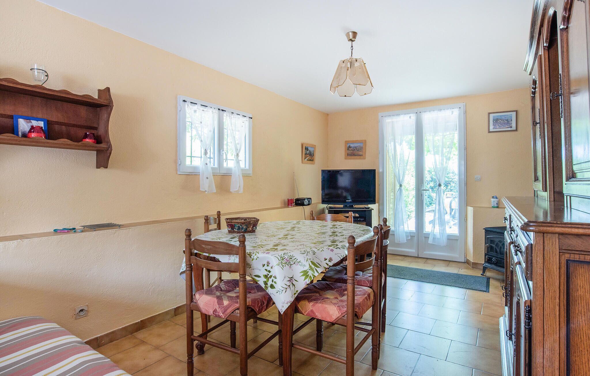 Un comedor con una mesa preparada para cuatro personas, un televisor y una chimenea.