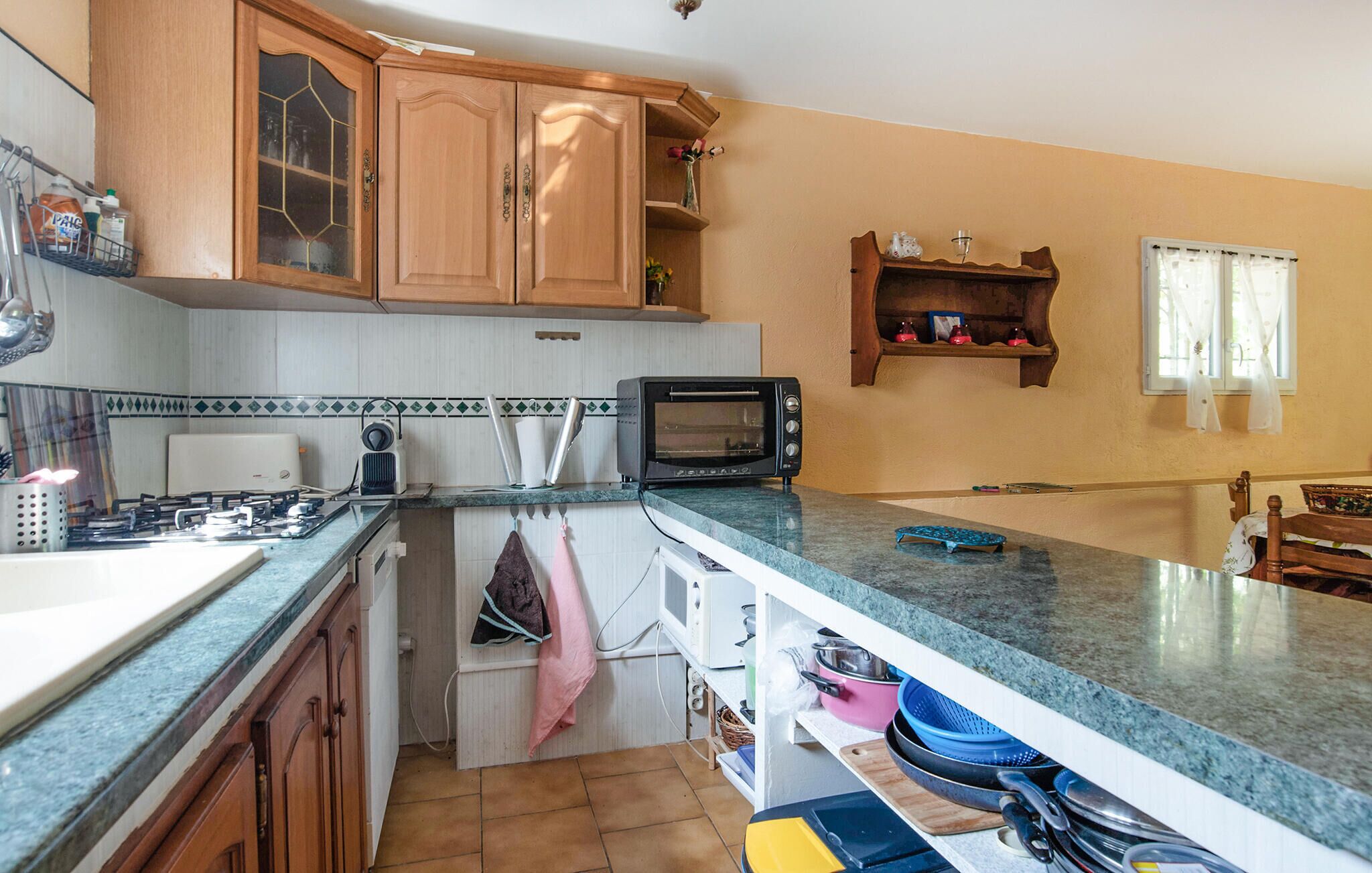 A kitchen with wooden cabinets, a microwave, and a countertop with various items.