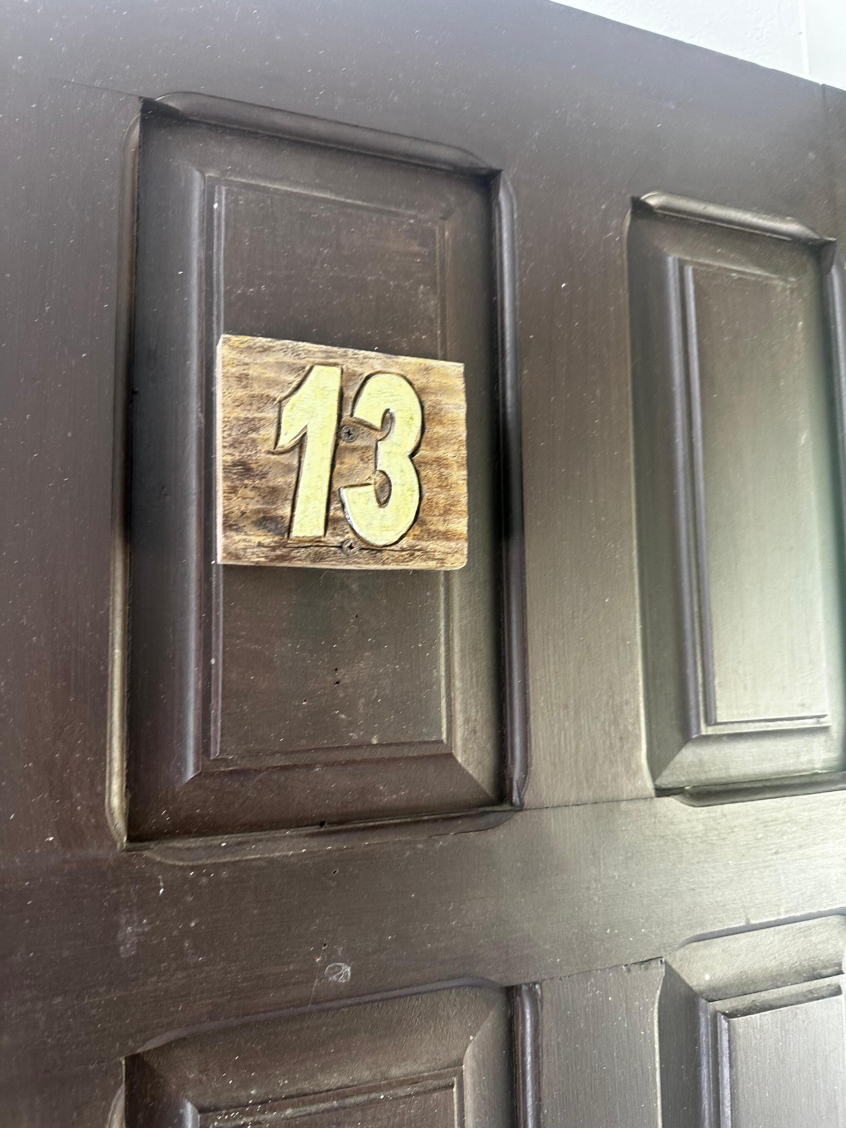 Una porta in legno scuro con una targa che riporta il numero 13.