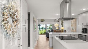 A modern kitchen with white cabinetry, a central island, and a view of the outdoors.