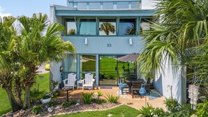 A modern two-story building with a number 33 sign, outdoor seating, and lush landscaping.