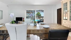 Un espace repas comprenant une grande table, des chaises et une vue sur une piscine et un coin salon extérieur.