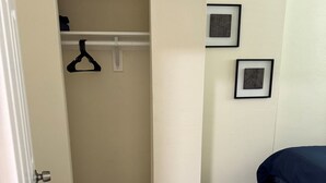 Une chambre avec un placard, un plancher en bois, un lit et deux tableaux encadrés au mur.