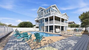 A two-story house with a pool, deck chairs, and a white fence. - 1397 - Sunshine Stars - Corolla Escape | Saltwater Pool & Hot Tub (Corolla)