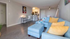 A modern living room with a blue sofa, yellow cushions, and a patterned throw.
