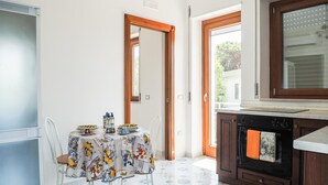 A kitchen with a dining table set for two, a stove, and a window with blinds. - Awesome apartment in Capaccio Paestum with WiFi (Capaccio Paestum)