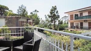 A balcony with wicker furniture, a white fence, and a view of a building with a balcony. - Awesome apartment in Capaccio Paestum with WiFi (Capaccio Paestum)