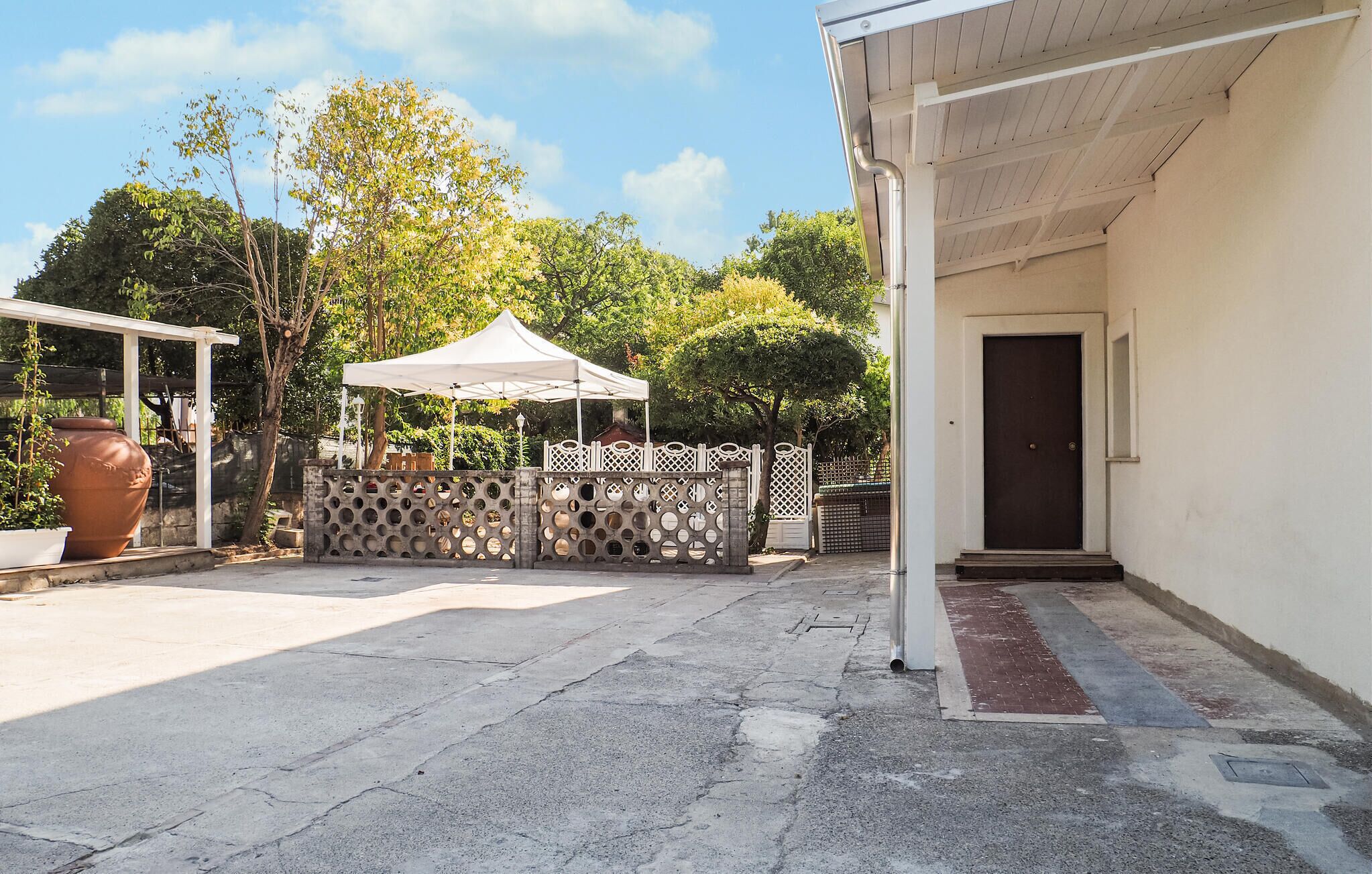A courtyard with a white tent, a large planter, and a gated entrance.