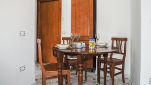 A dining area with a round wooden table, four chairs, and a decorative ceramic jug. - 1 bedroom awesome apartment in Capaccio Paestum (Capaccio Paestum)