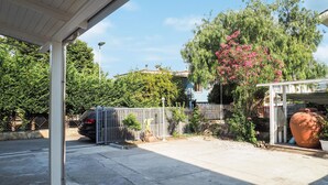 A covered outdoor area with a car parked in the background, surrounded by greenery and a large potted plant. - 1 bedroom awesome apartment in Capaccio Paestum (Capaccio Paestum)