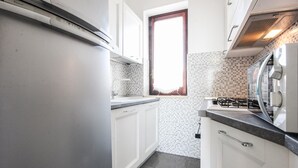 A kitchen with white cabinets, a tiled backsplash, a window, and a stove.