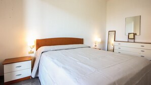 A bedroom with a bed, bedside tables, a dresser, a mirror, and wall-mounted lights.