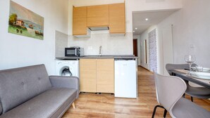 Une cuisine compacte équipée d’un lave-linge, d’un four à micro-ondes et de meubles de rangement en bois.