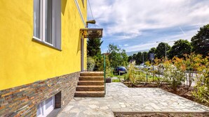 Un bâtiment jaune avec un chemin de pierre menant à un ensemble de marches en bois.