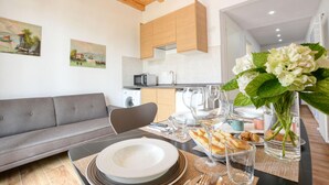 Une cuisine moderne avec des meubles en bois, un coin repas avec une table mise pour deux personnes et un canapé gris.
