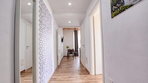 Un couloir doté d’un plancher en bois, de murs blancs et d’un mur d’accent en briques.